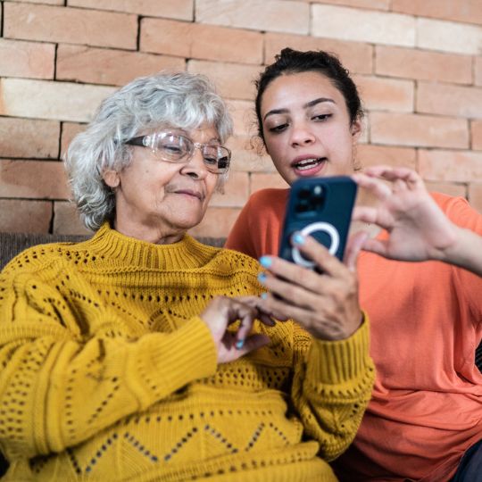 73_9282_10Jan2025093244_Teenager helping senior woman to use the mobile phone 540px.jpg